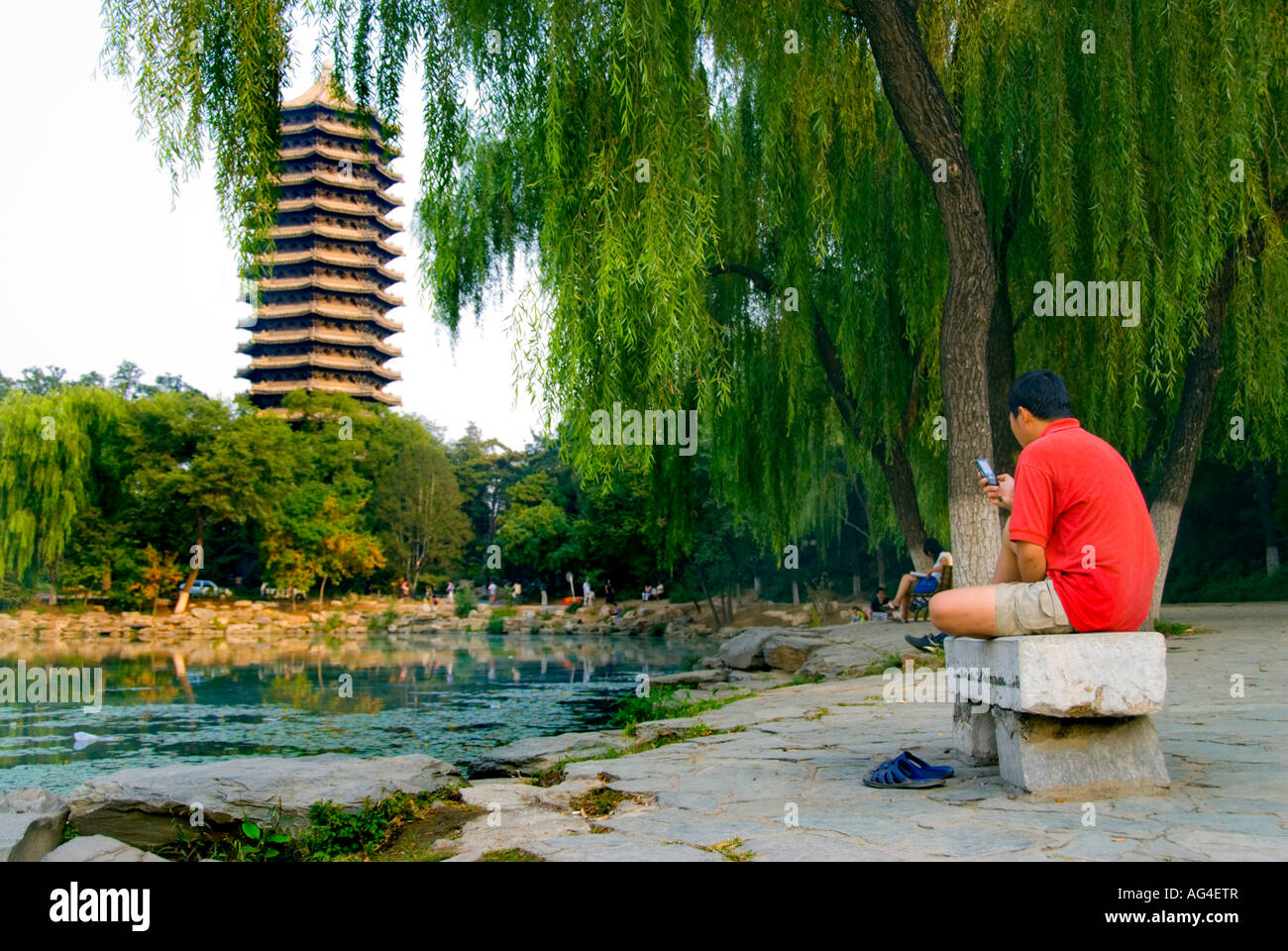 Peking CHINA, Bildung „Peking Universität“ Campus Blick auf den See mit Pagode männlicher Student mit Mobiltelefon draußen Stockfoto