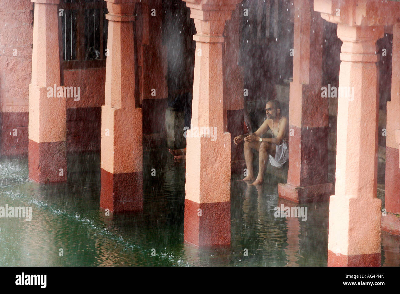 ein Mann wacht den Regen während des Monsuns im Tempel in Indien Stockfoto