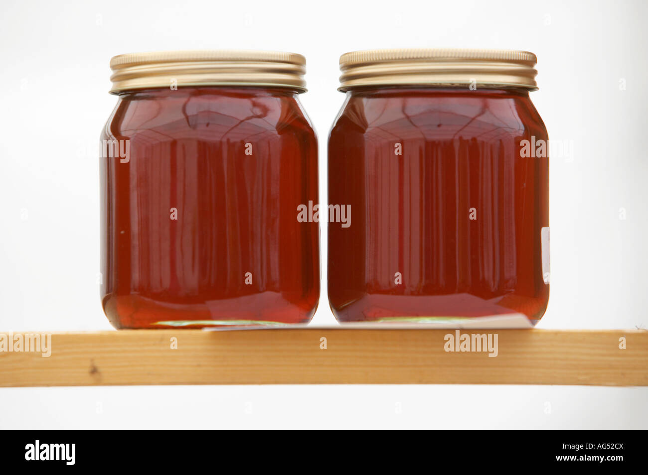 zwei Gläser mit dunklem Honig sitzt auf einem Holzregal Stockfoto
