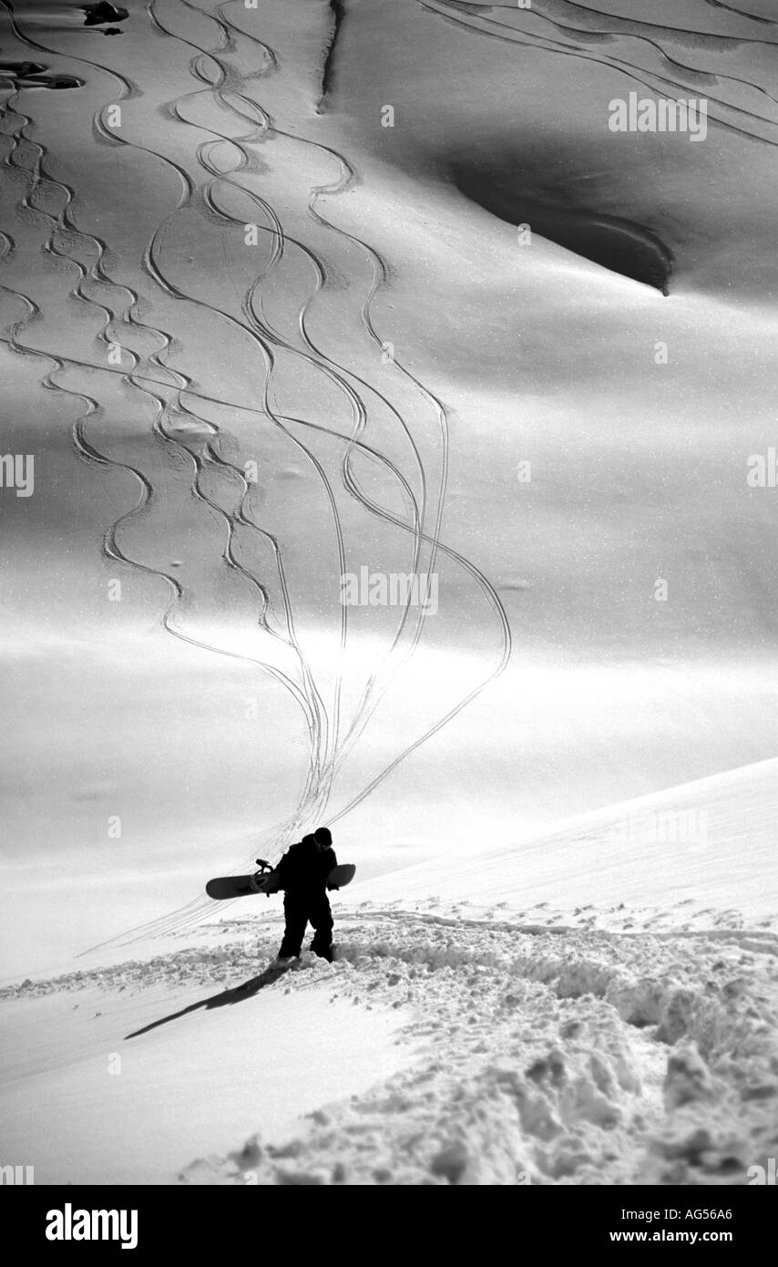 Einsamer Snowboard am Hang mit seinem Snowboard den Berg hinauf Stockfoto