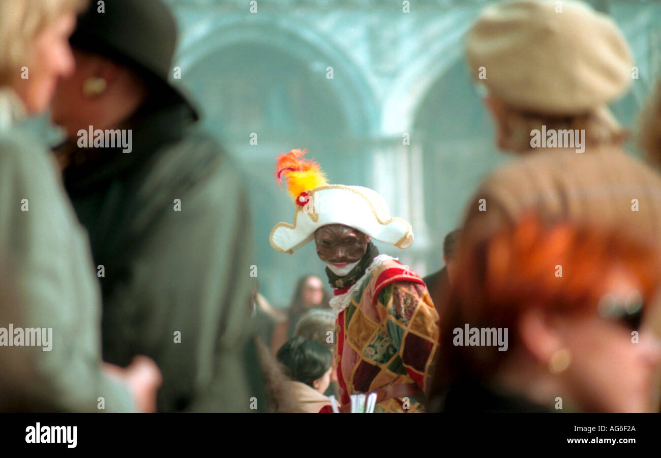 Eine maskierte Person gekleidet wie ein Harlekin mit Kokarde Hut in einem Café in Saint Markusplatz in Venedig während des Karnevals Stockfoto