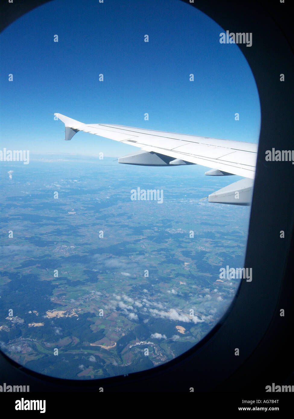 Fenster und Flügel im Flug an Bord eines Flugzeugs im blauen Himmel über Bayern. Foto: Willy Matheisl Stockfoto