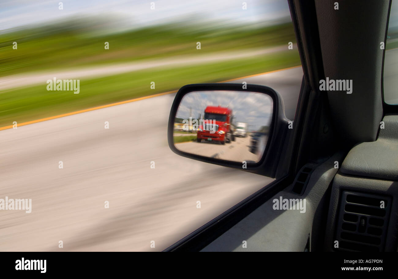 hintere Ansicht Auto Spiegel zeigen rote LKW Auto vorbei zu beschleunigen Stockfoto