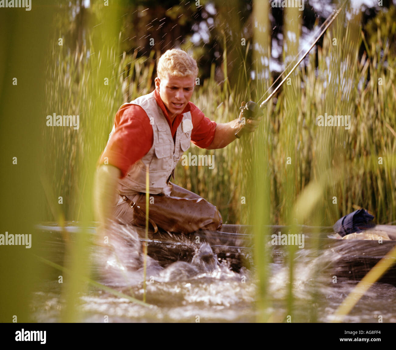 Mensch Fang von Fischen vom kleinen Boot unter Rohrkolben Stockfoto