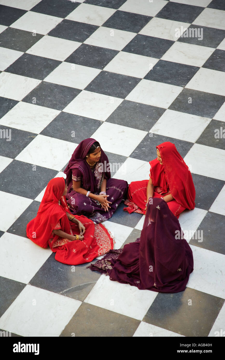 Indische Frauen in traditionellen Saris sitzen auf dem karierten Boden von Peacock Hof Stadt Palast Komplex Udaipur, Indien Stockfoto