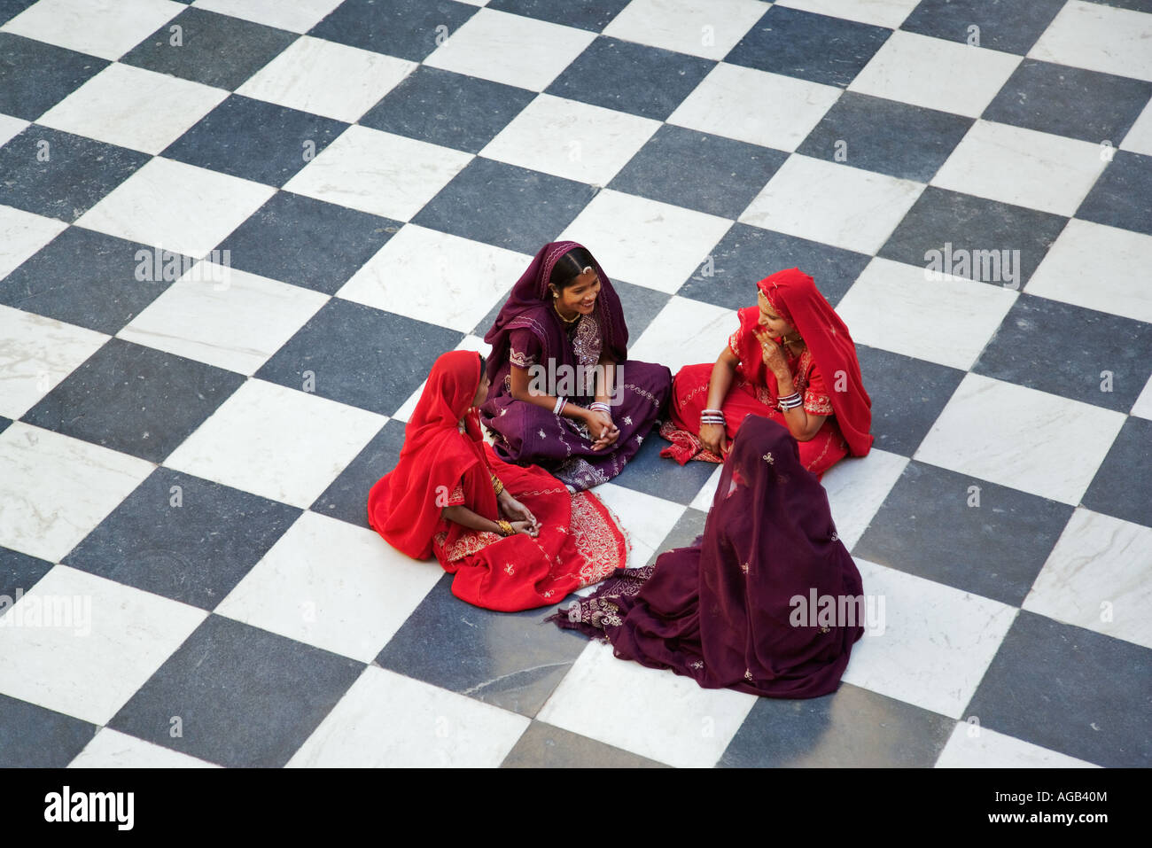 Indische Frauen in traditionellen Saris auf dem karierten Boden sitzen. Peacock Hof in der Stadt-Palast Komplex Udaipur-India Stockfoto