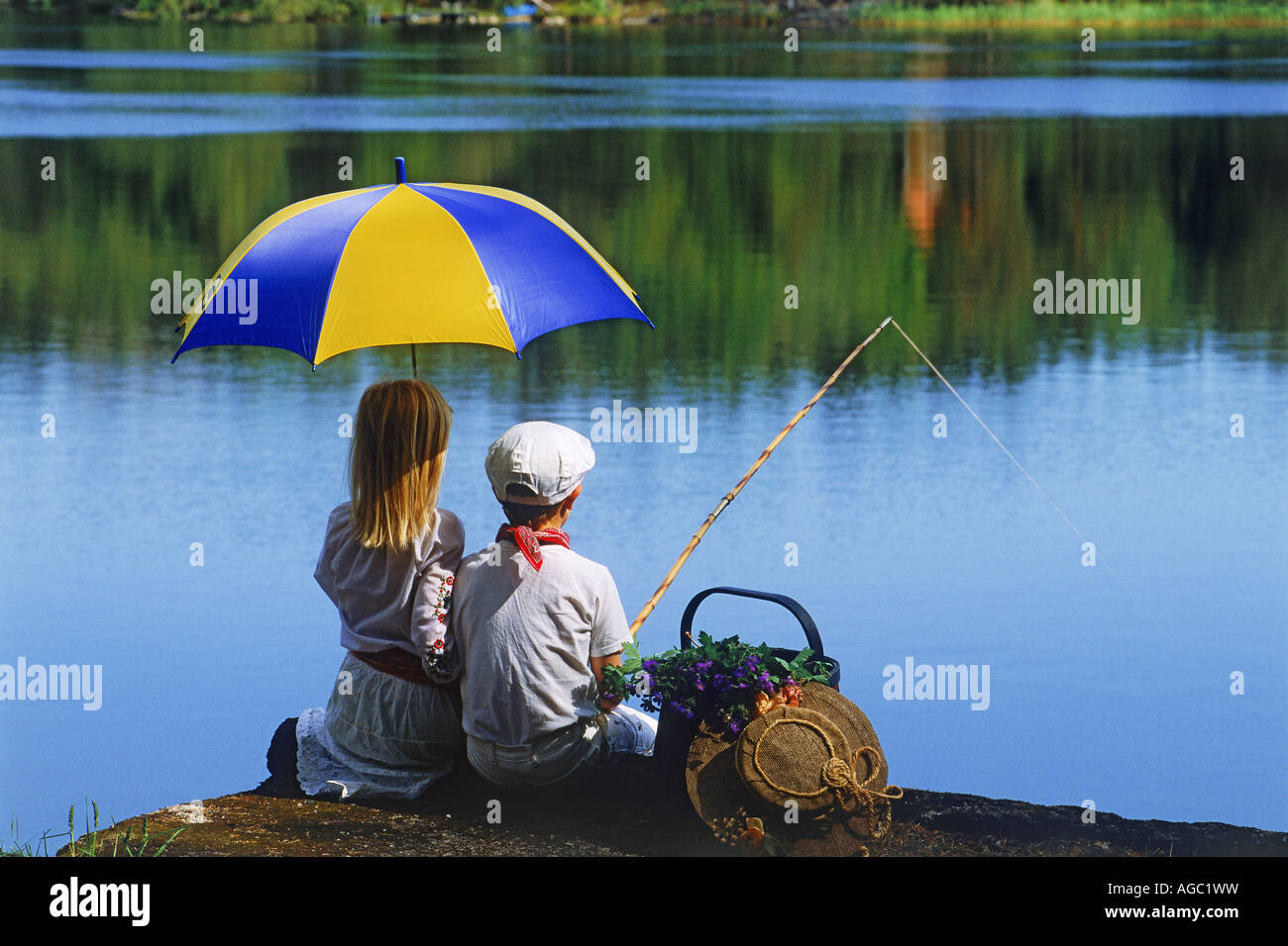 Zwei Kinder 5-10 Jahre auf Angeln Picknick mit schwedischen Nationalfarben auf Regenschirm Stockfoto