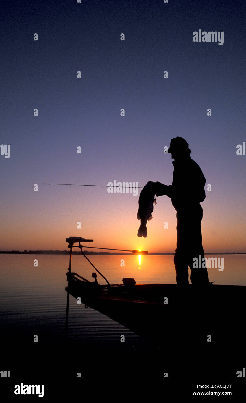 Forellenbarsch Fischen Sonnenaufgang Silhouette Angler halten Trophäe bass Stockfoto