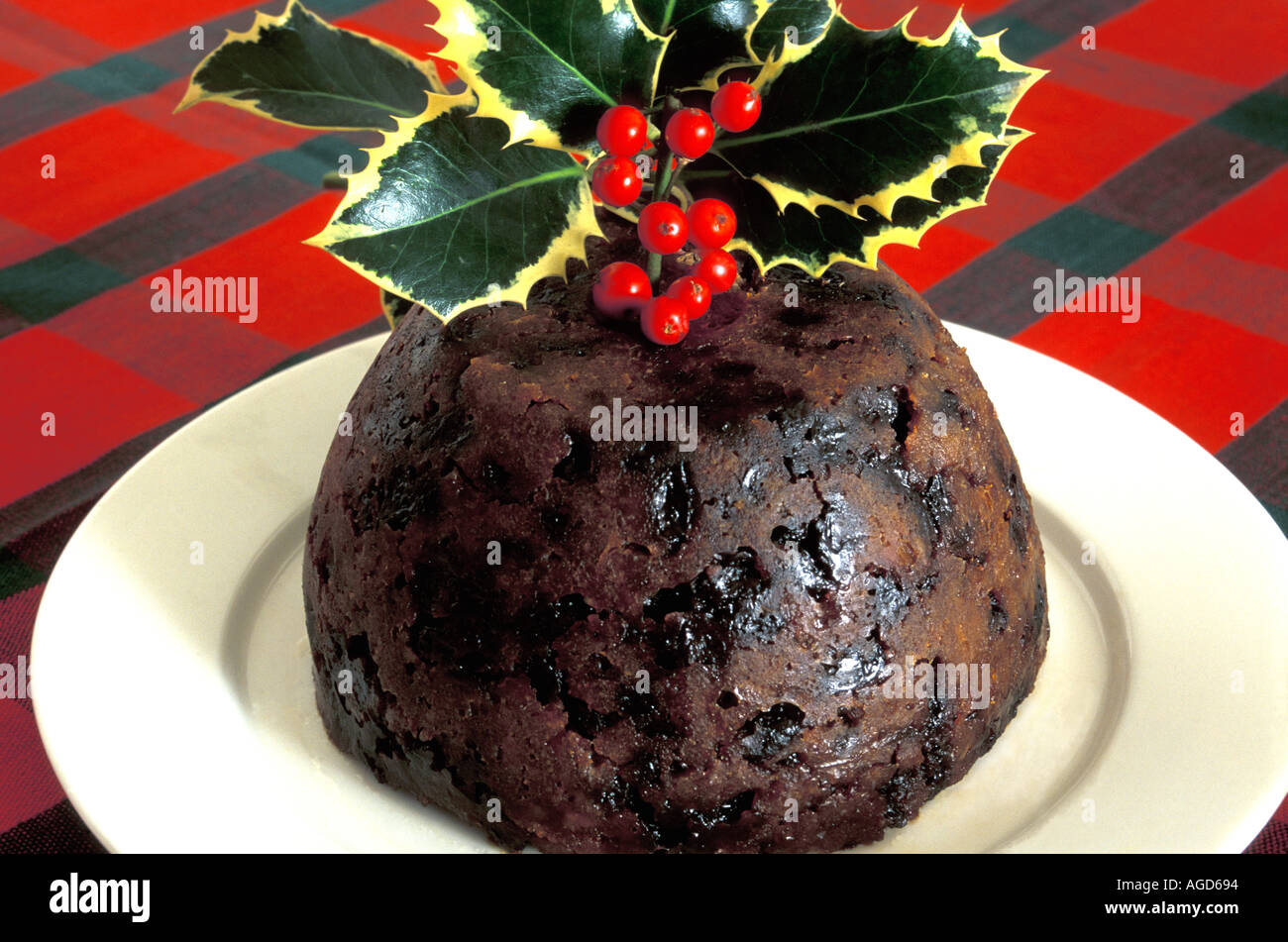 Christmas Pudding dekoriert mit Holly auf weißen Teller. Stockfoto