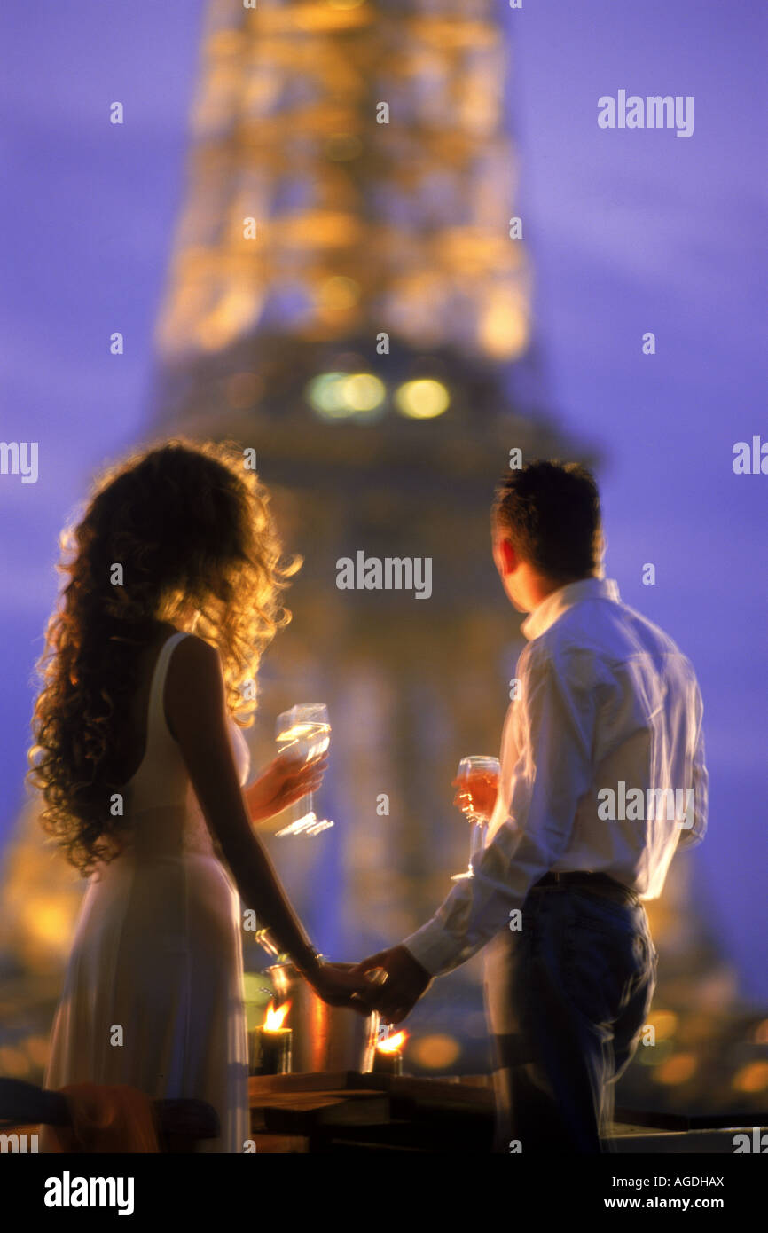 Paar mit Gläsern Champagner am Ufer Hausboot unter Eiffelturm bei Nacht Stockfoto