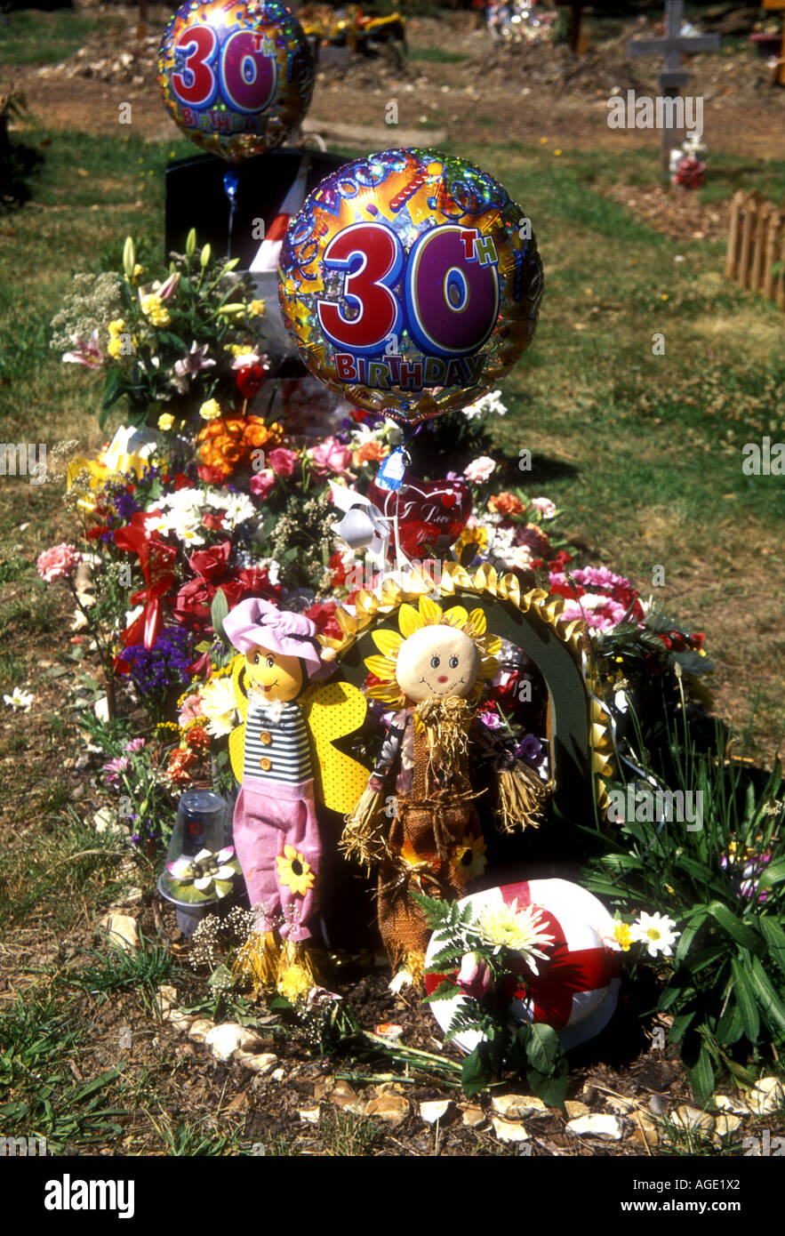 Christliches Grab auf einem englischen Friedhof mit Geschenken zum Geburtstag eines geliebten Menschen. Stockfoto