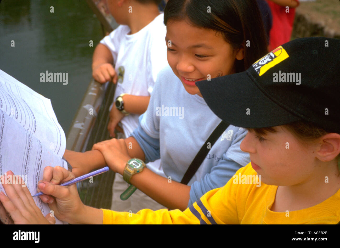 Mädchen Alter 11 schreiben in Notebook in der Schule. Hong Kong China Asien Stockfoto
