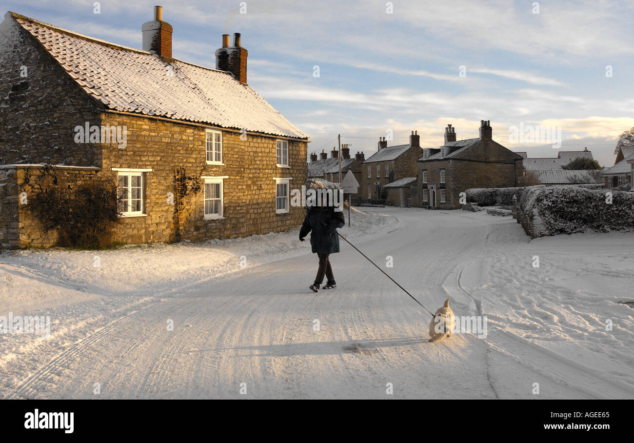 Spaziergang mit dem Hund im Winterschnee in einem Dorf North Yorkshire, Vereinigtes Königreich. Stockfoto