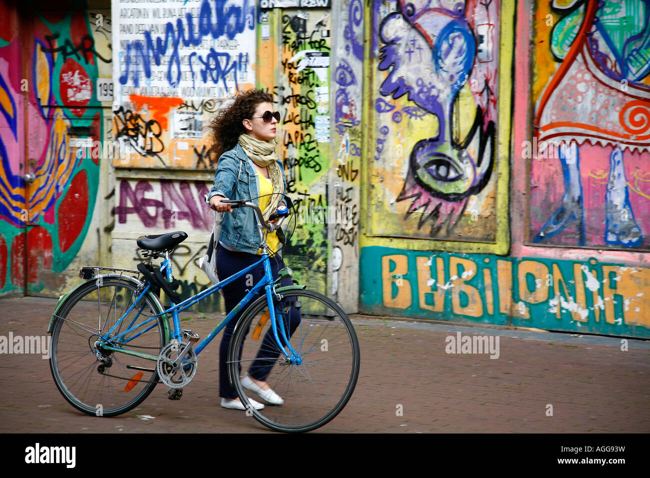 Junge Frau, die zu Fuß durch eine gemalte Wand auf Spuistraat Amsterdam Holland Stockfoto