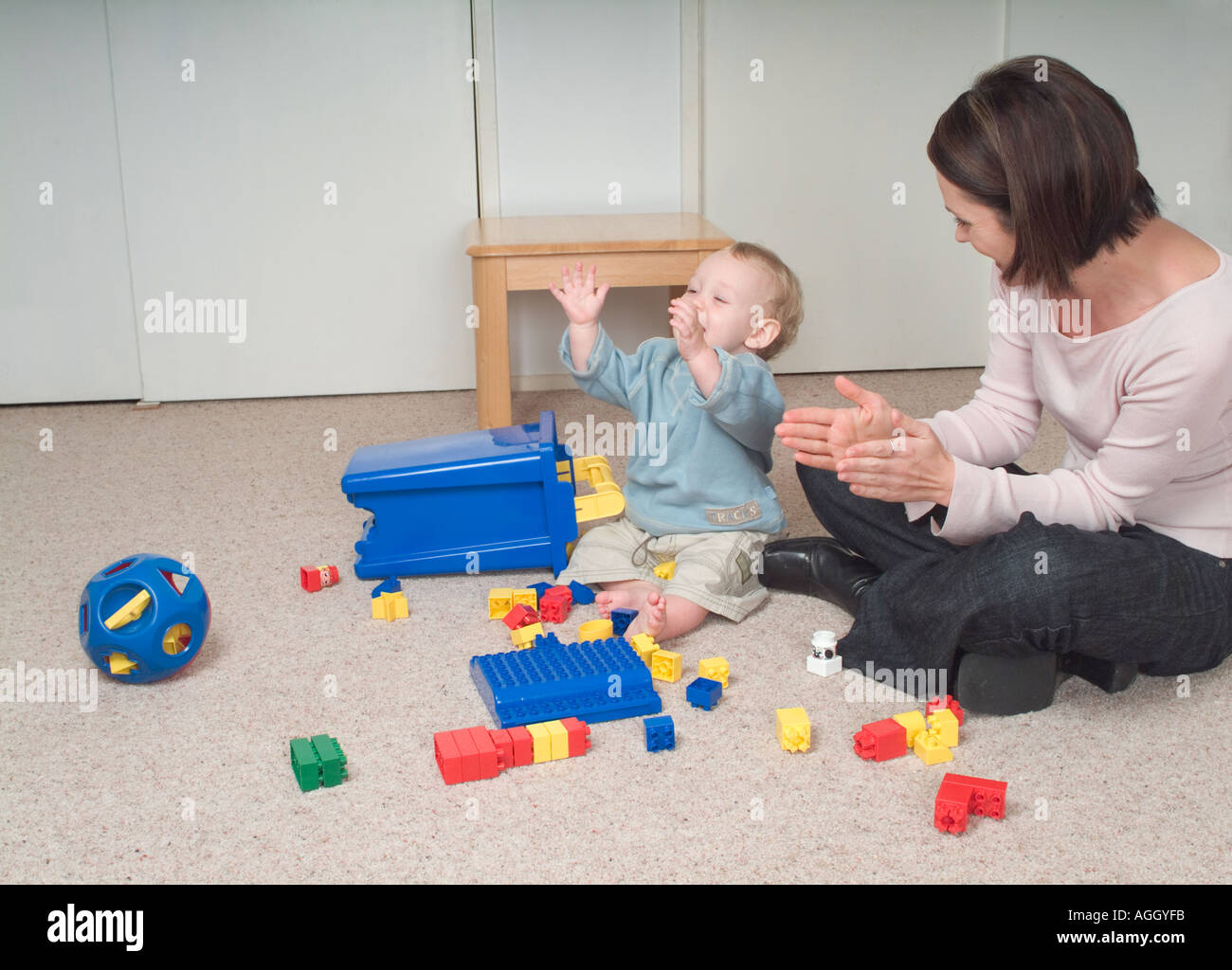 Mutter Und Baby Sohn Auf Dem Boden Sitzend Lernt Das Kind Seine Hande Klatschen Stockfotografie Alamy