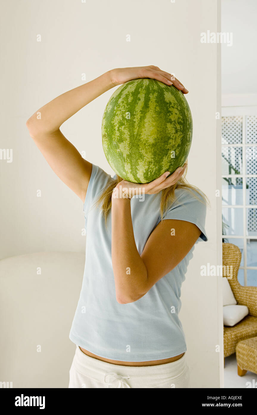 Frau Holding Wassermelone über Gesicht Stockfoto