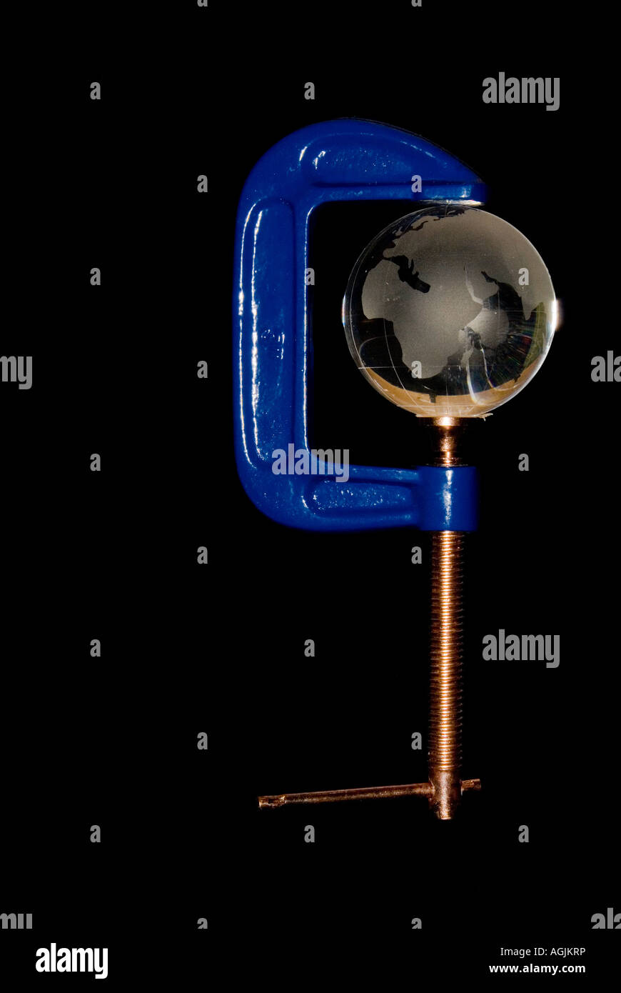 Eine Glaskugel, die in einer C Clamp konzeptionell unter Angabe der Welten Ressourcen unter Druck gehalten Stockfoto