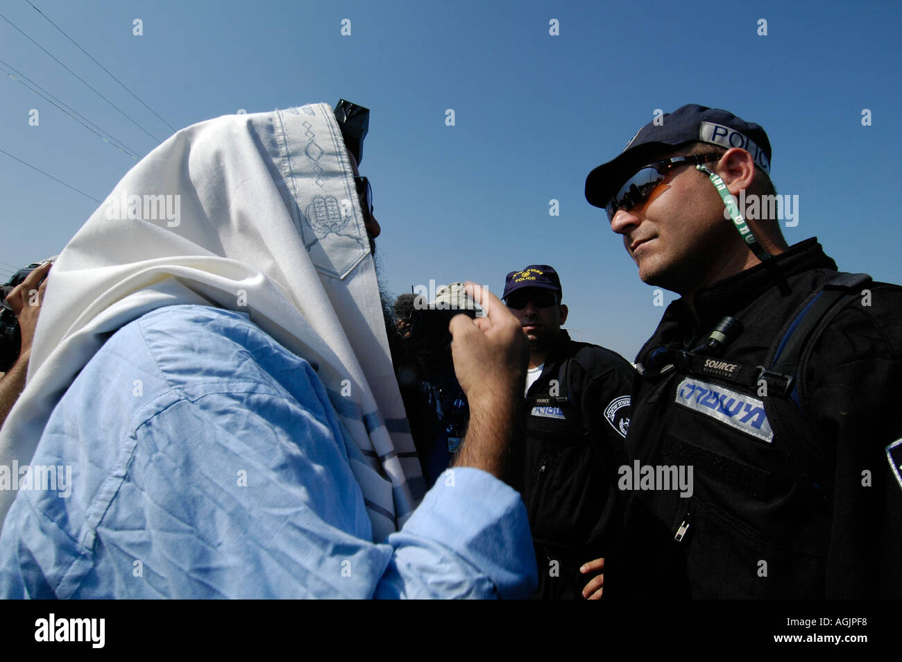 Ein religiöser jüdischer Siedler mit einem Talit Schal und eingewickelt Tfilin konfrontiert die israelische Polizei während der Evakuierung jüdischer Siedlungen aus Gaza Streifen Stockfoto