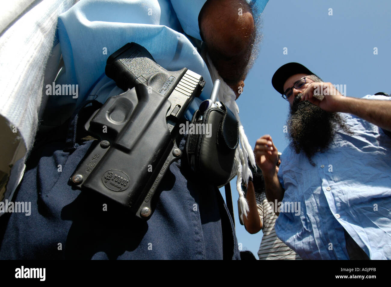 Eine religiöse jüdische Siedler, vor denen ein bewaffneter Polizist während der Evakuierung der jüdischen Siedlungen im Gazastreifen Stockfoto