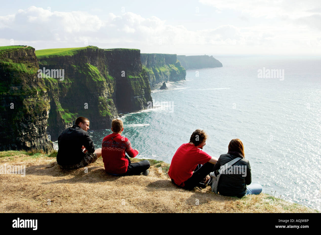 Junge Leute sitzen am Rand von den Cliffs of Moher im County Clare West Irland Stockfoto