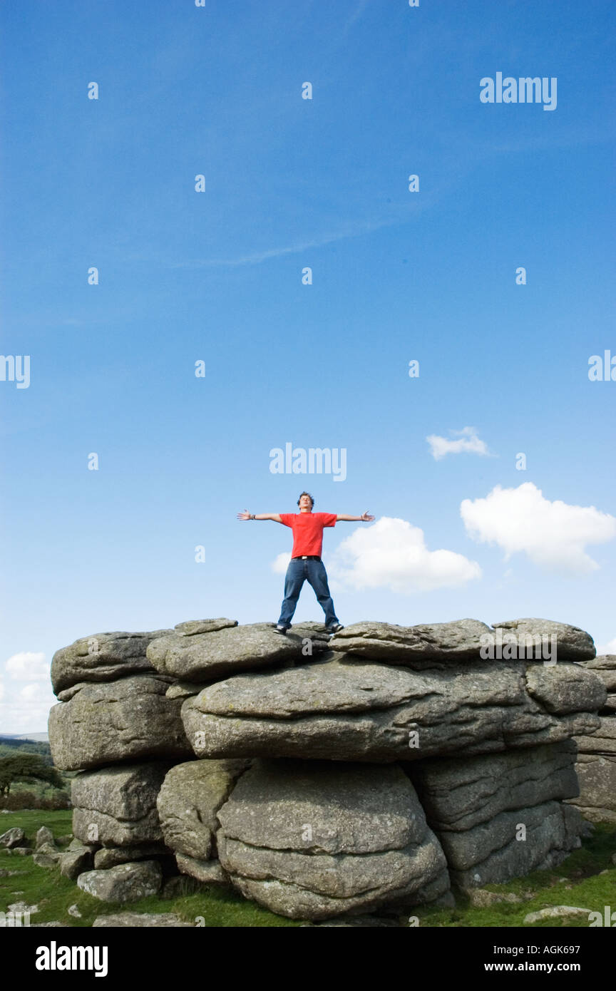Junger Mann mit ausgestreckten Armen auf einem Felsen stehend Stockfoto