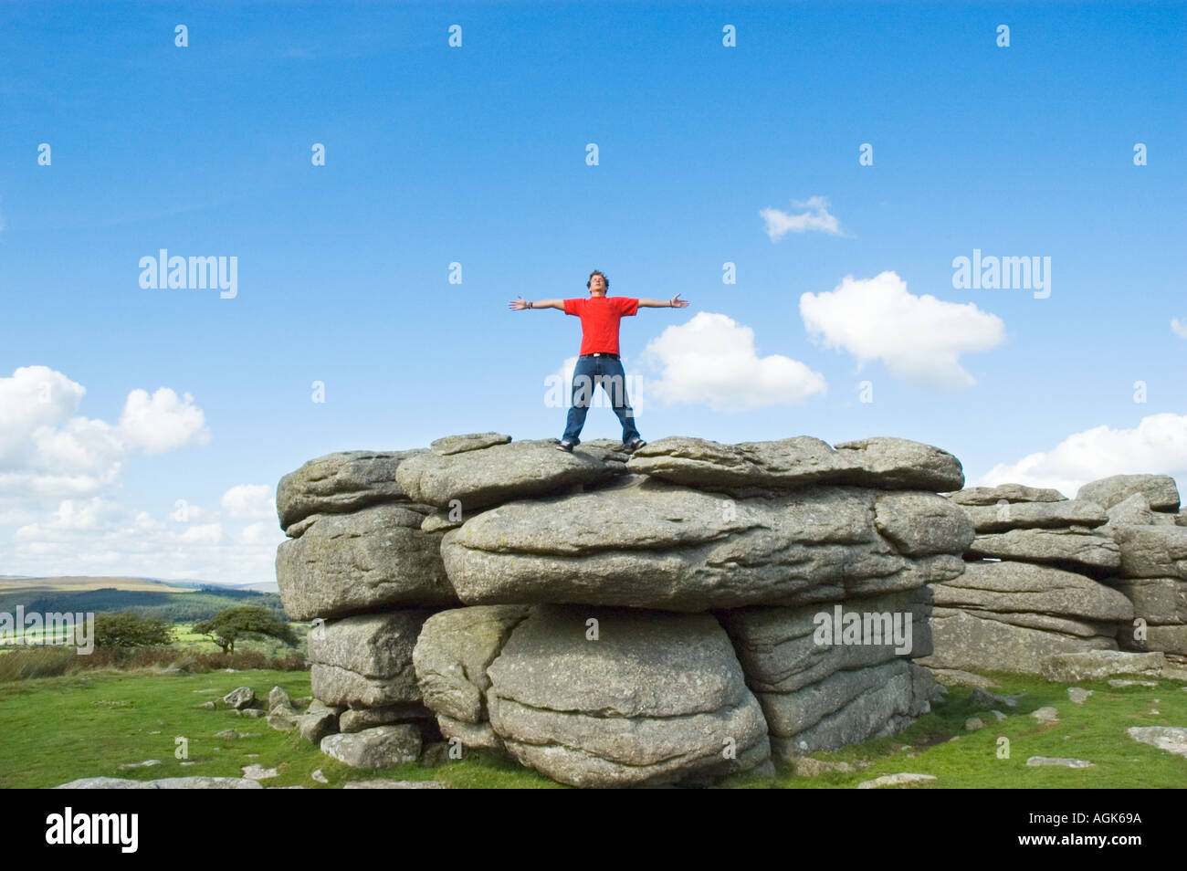 Junger Mann mit ausgestreckten Armen auf einem Felsen stehend Stockfoto