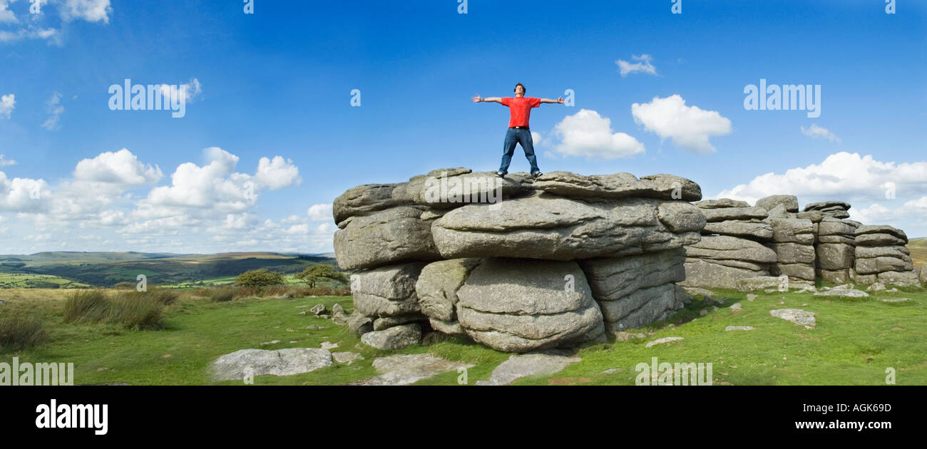 Junger Mann mit ausgestreckten Armen auf einem Felsen stehend Stockfoto