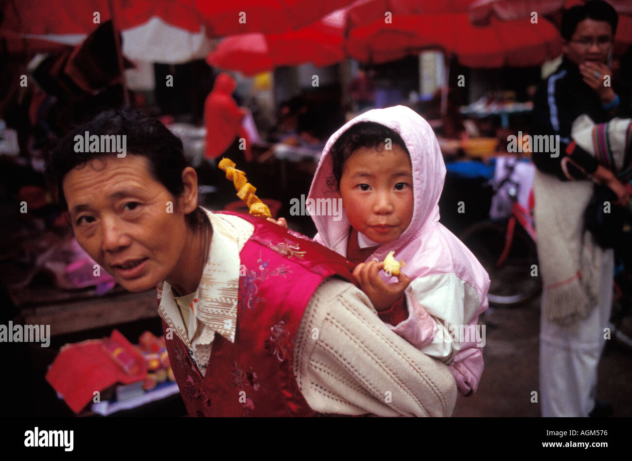 Tibetische Frau in traditioneller Kleidung mit Tochter auf dem Rücken Zhongdian County Provinz Yunnan China Stockfoto