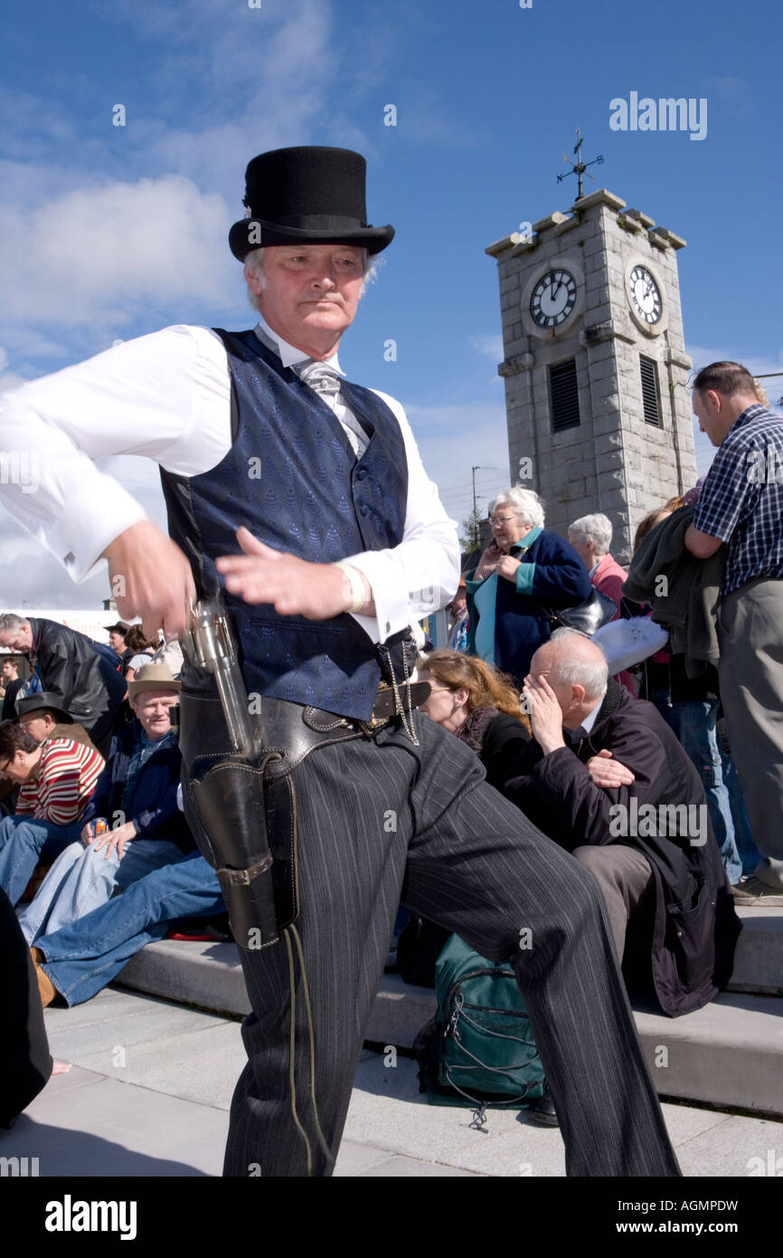 Schottische Veranstaltungen Creetown Country Music Festival Cowboy posiert mit Gewehr auf dem Platz mit Clocktower hinter Galloway Scotland UK Stockfoto