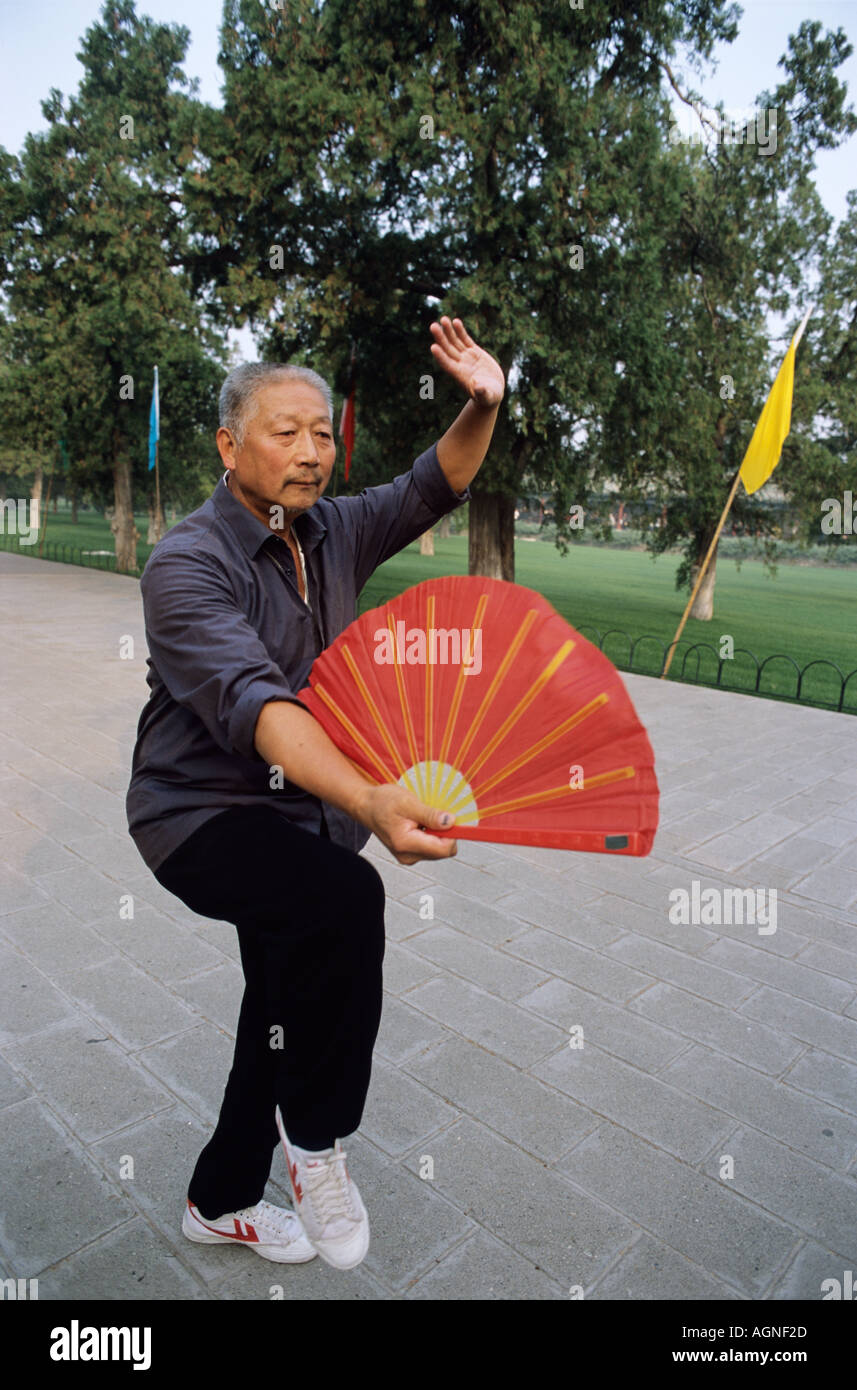 Mann mit rotem Ventilator führt Tai Chi Übungen bei Sonnenaufgang Tempel des Himmels Peking China Stockfoto