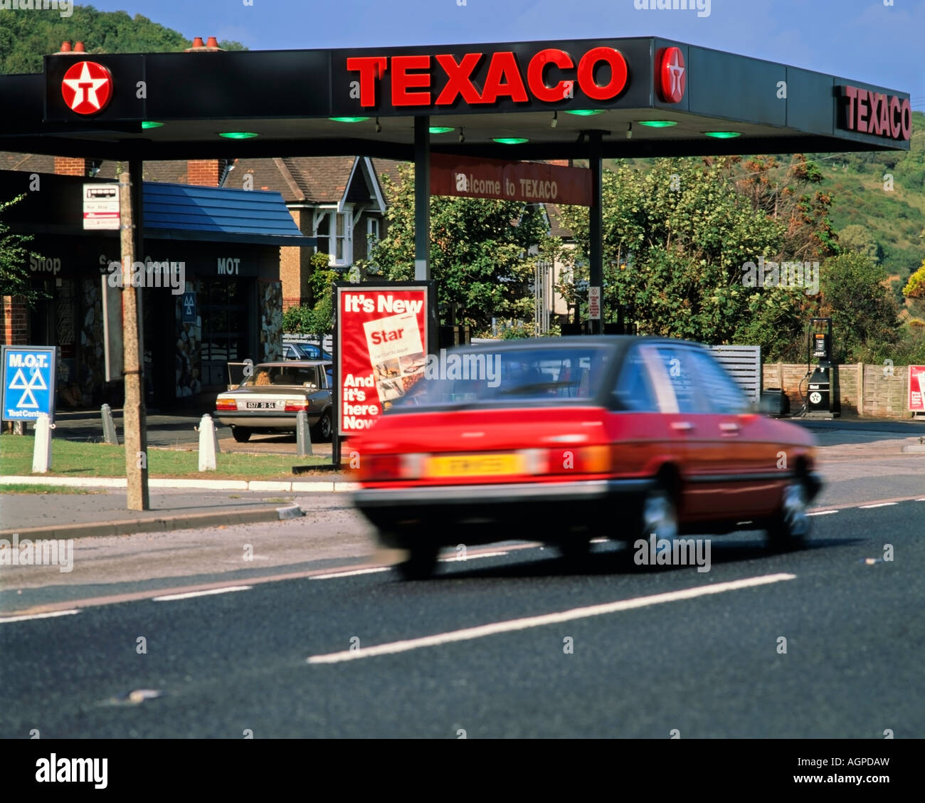Rotes Auto vorbei an Texaco Tankstelle, Autos und Straßen Stockfoto Rotes Auto vorbei an Texaco Tankstelle, Autos und Straßen Stockfoto
