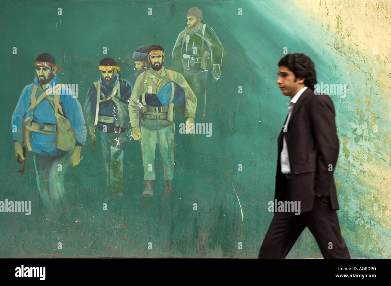 Ein Mann in einem Anzug zu Fuß vor einem Gemälde die Krieger aus dem Iran und dem Irak-Krieg an den Außenwänden des EX-US-e Stockfoto