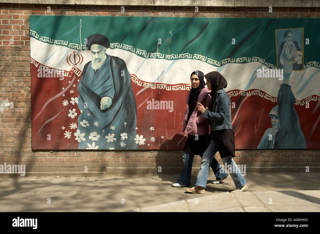 Zwei Frau tragen islamische Uniformen zu Fuß vor dem Gemälde von Ayatollah Khomeini und der iranischen Flagge auf außen Wände Stockfoto