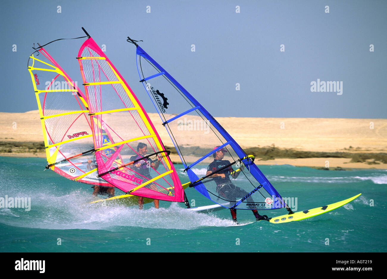 Drei Windsurfer Segeln extrem nah beieinander in einer Gruppe am Roten Meer in Ras Sudr Sinai Ägypten mit heißen sonnigen Sandstrand im Hintergrund Stockfoto