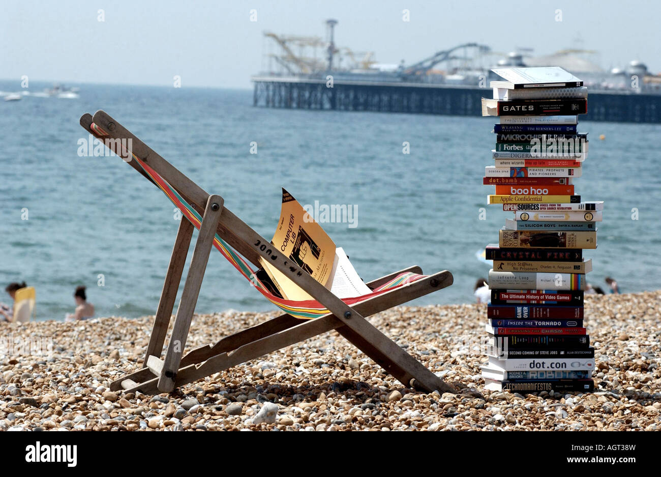 Ernst Sommer Lesung. Ein Stapel von Fachbücher auf einem Liegestuhl am Strand von Brighton mit dem Pier im Hintergrund Stockfoto