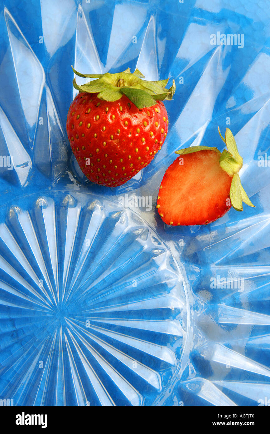 SSK79559 Frucht zwei frische rote Erdbeeren im Schnitt Glasplatte vor blauem Hintergrund Stockfoto