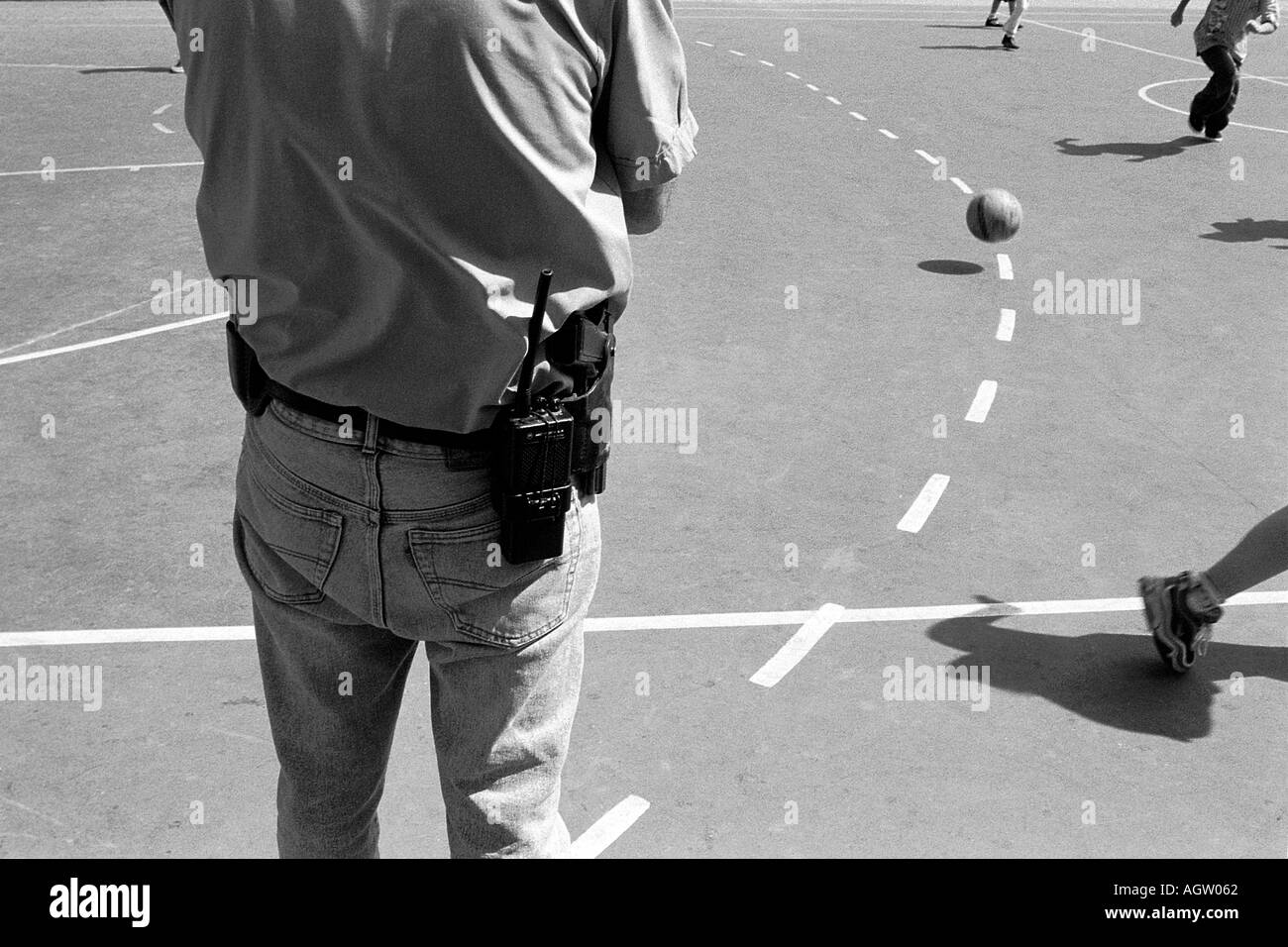 Ein Mann stand Guard als Schulkinder spielen Fußball im Hof von Tel Nordoi primary school in Tel Aviv, Israel Stockfoto