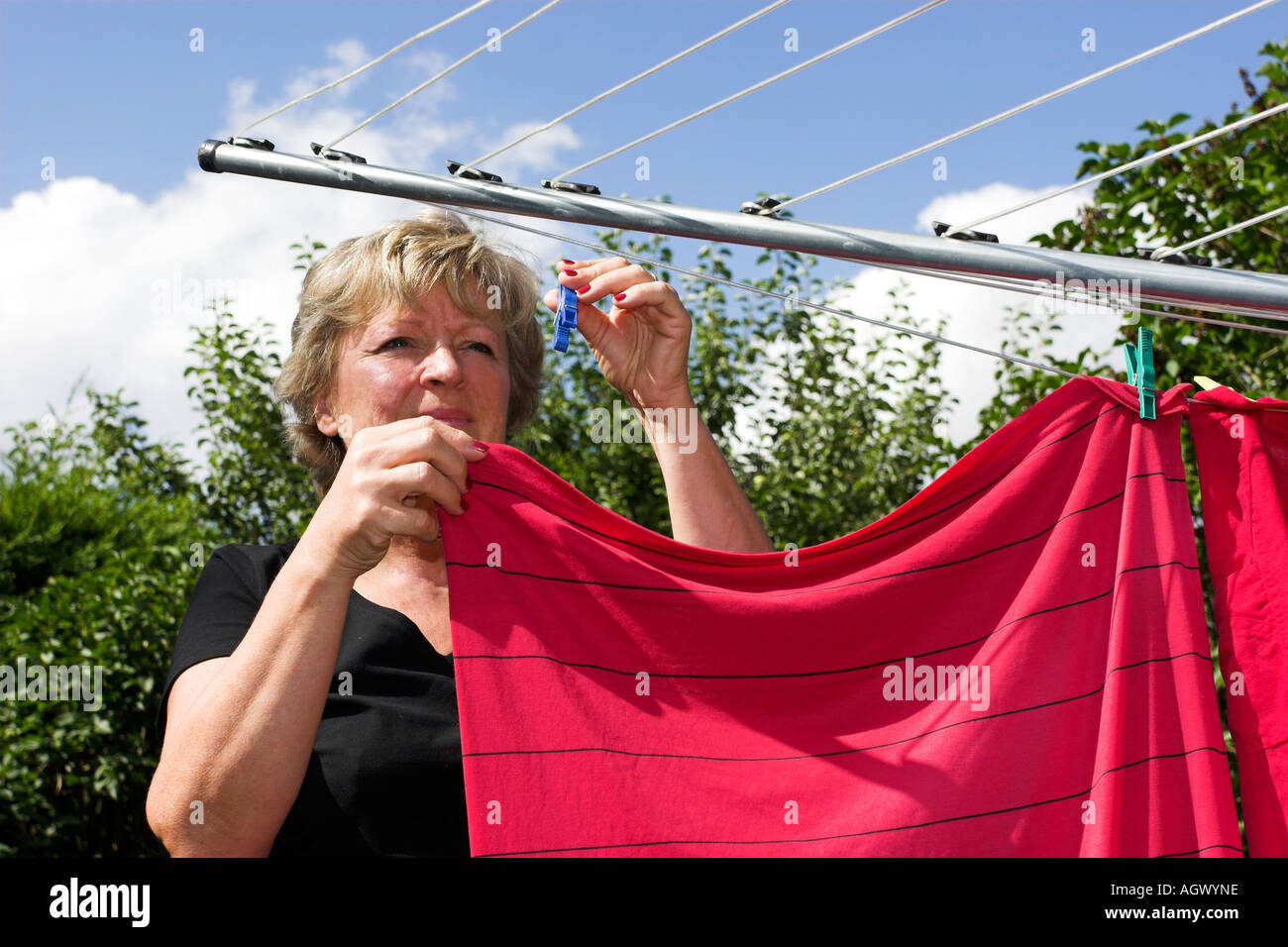 Frau Aufhängen von Wäsche auf Linie im Garten. Stockfoto