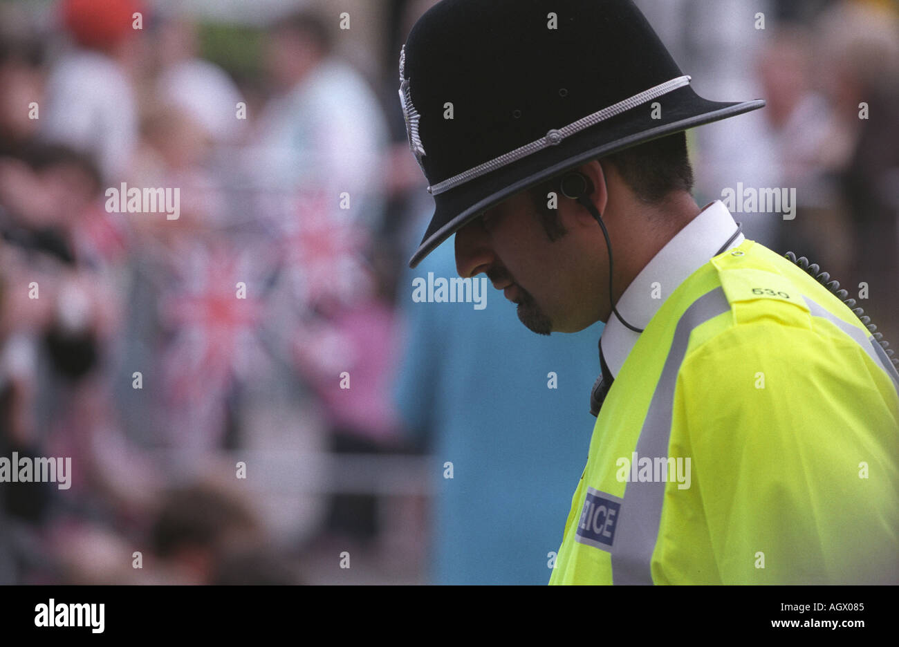 Polizist blickte auf den Boden in Leuchtweste und traditionellen Polizeihelm Kommunikation anhören Stockfoto