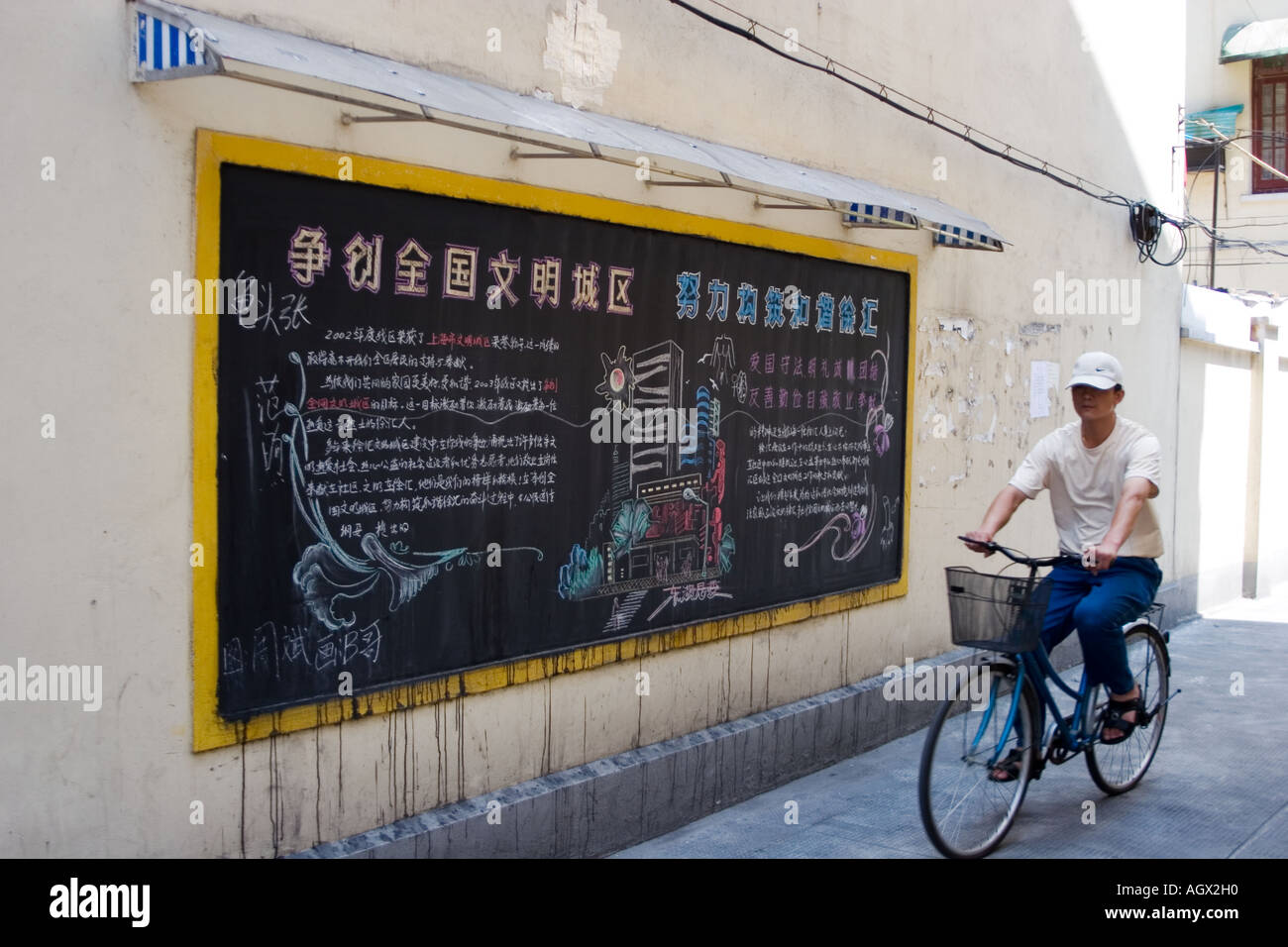 In einer Gasse mit Huai Hai Lu Xin Le Lu verbinden Zyklen ein Mann vorbei an einer Tafel neben einer Schule. Shanghai. Stockfoto