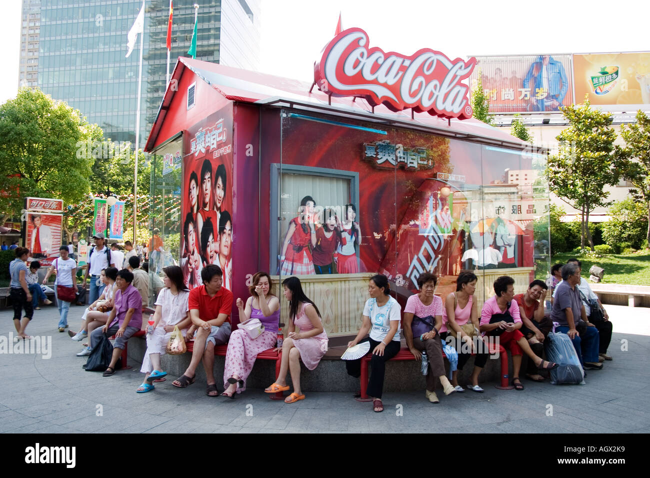 Arbeitnehmer sitzen zur Mittagszeit vor Coca Cola Werbung in Shanghais beliebte Xiang Yang Modemarkt im Schatten. Stockfoto