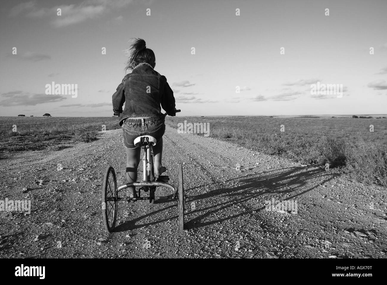 Junge Mädchen Reiten Fahrrad auf einer staubigen Straße Australien Stockfoto