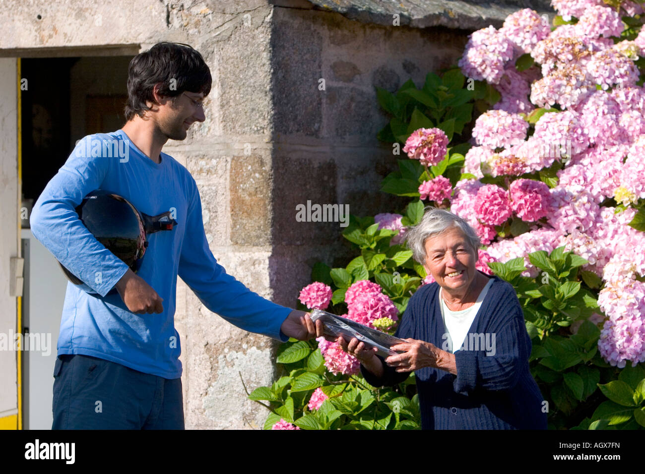 Französischer Briefträger Zustellung einer älteren Frau in der Gemeinde von Barfleur in der Region Basse-Normandie-Frankreich Stockfoto