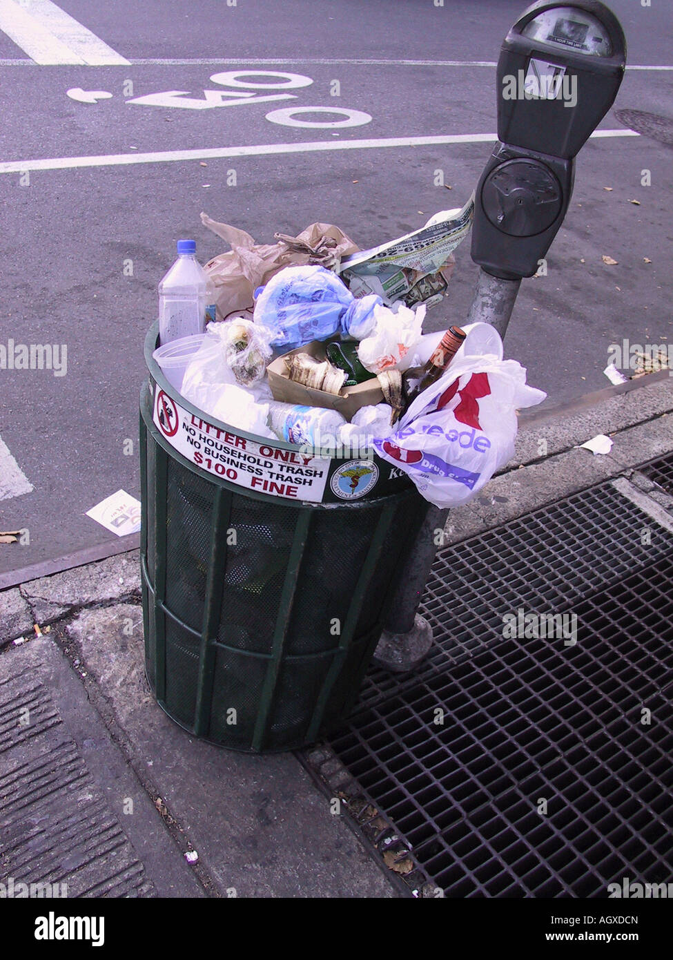 Mülltonne auf Stadtstraße mit Parkuhr überfüllt. Wurf, Geldstrafe von nur 100 $ auf Schild, Konzept der Abfälle, Plastik, Müll, urbane Stadtzentrum Stockfoto