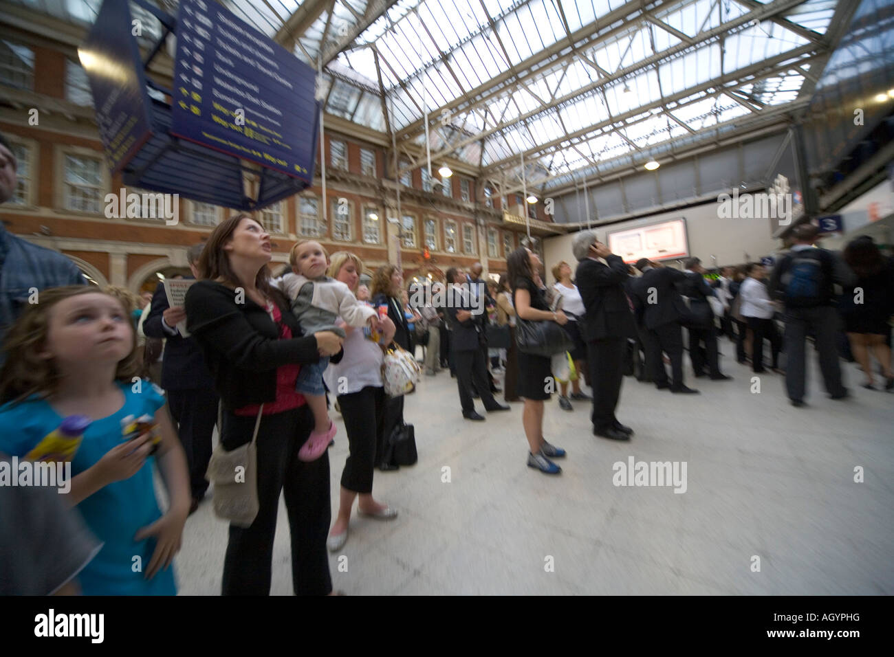 Mutter mit Kindern und Pendler vor Verzögerungen Check Fahrplan an der Waterloo Station-London Stockfoto