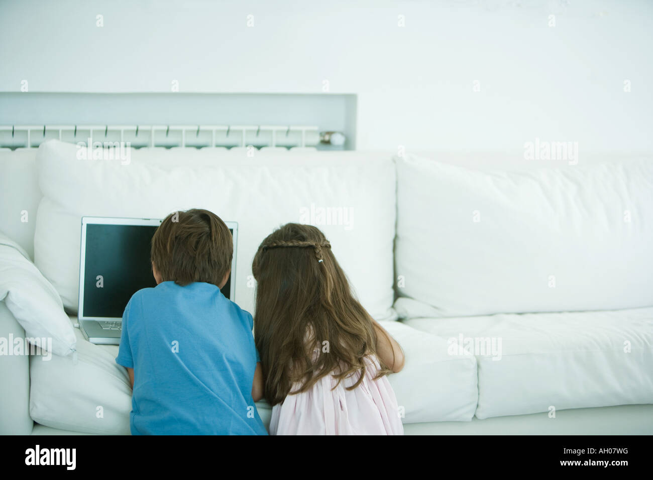 Jungen und Mädchen mit Laptop auf Sofa, Rückansicht Stockfoto