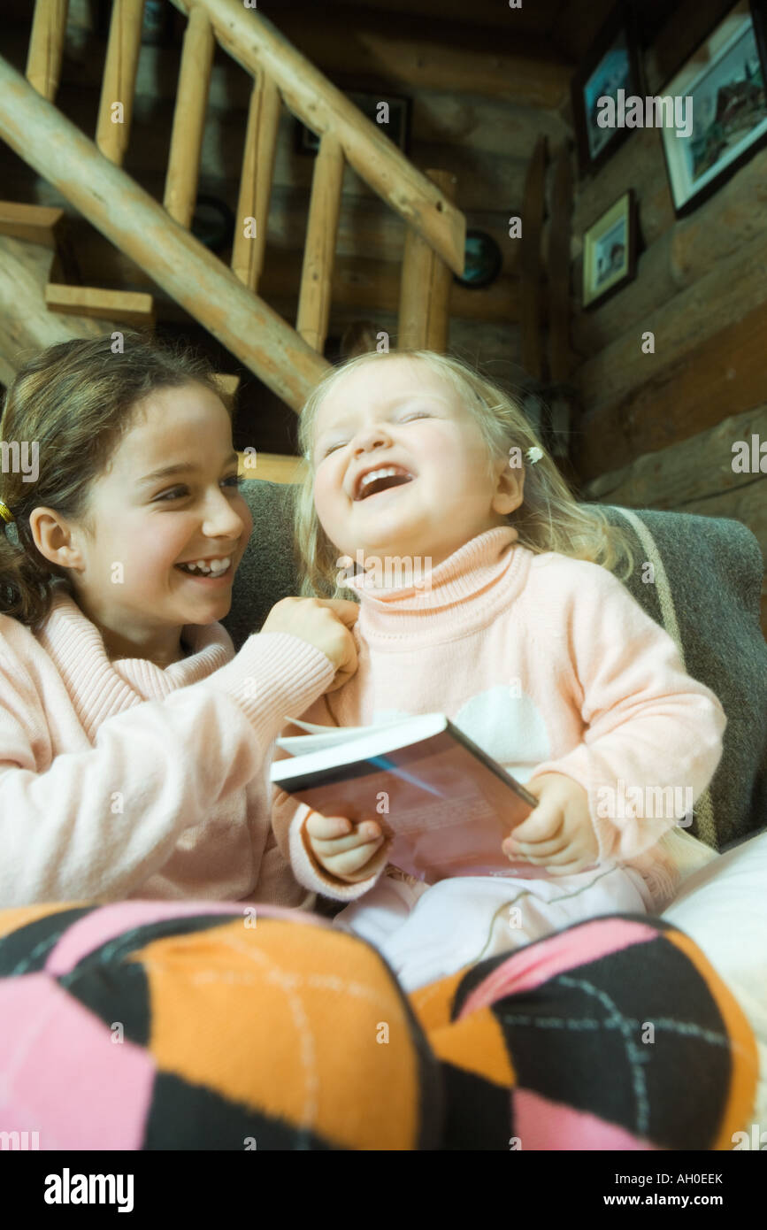 Mädchen und Kleinkind auf Couch sitzen, lachen Stockfoto