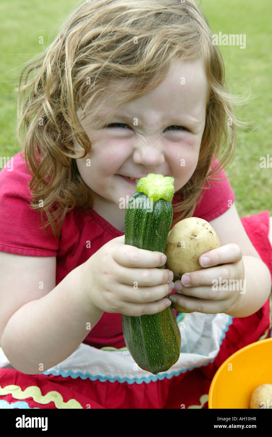 Kleines Kind hält home Anbau mit Stolz. Eine Kartoffel und Zucchini Stockfoto