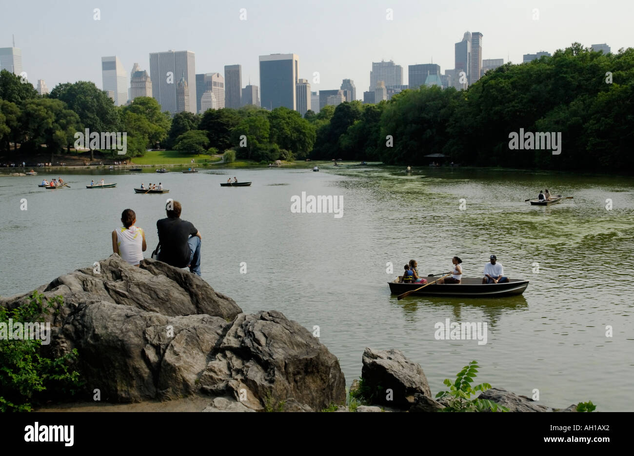 Junges Paar Blick auf Central Park Lake mit Bootsfahrer und Skyline von New York City, Manhattan Stockfoto