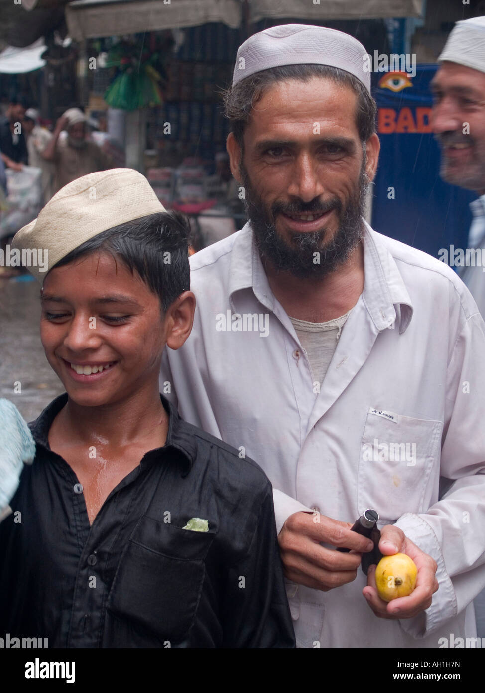eine Litschi-Verkäufer und sein Sohn bei Regen in Peshawar, Pakistan Stockfoto